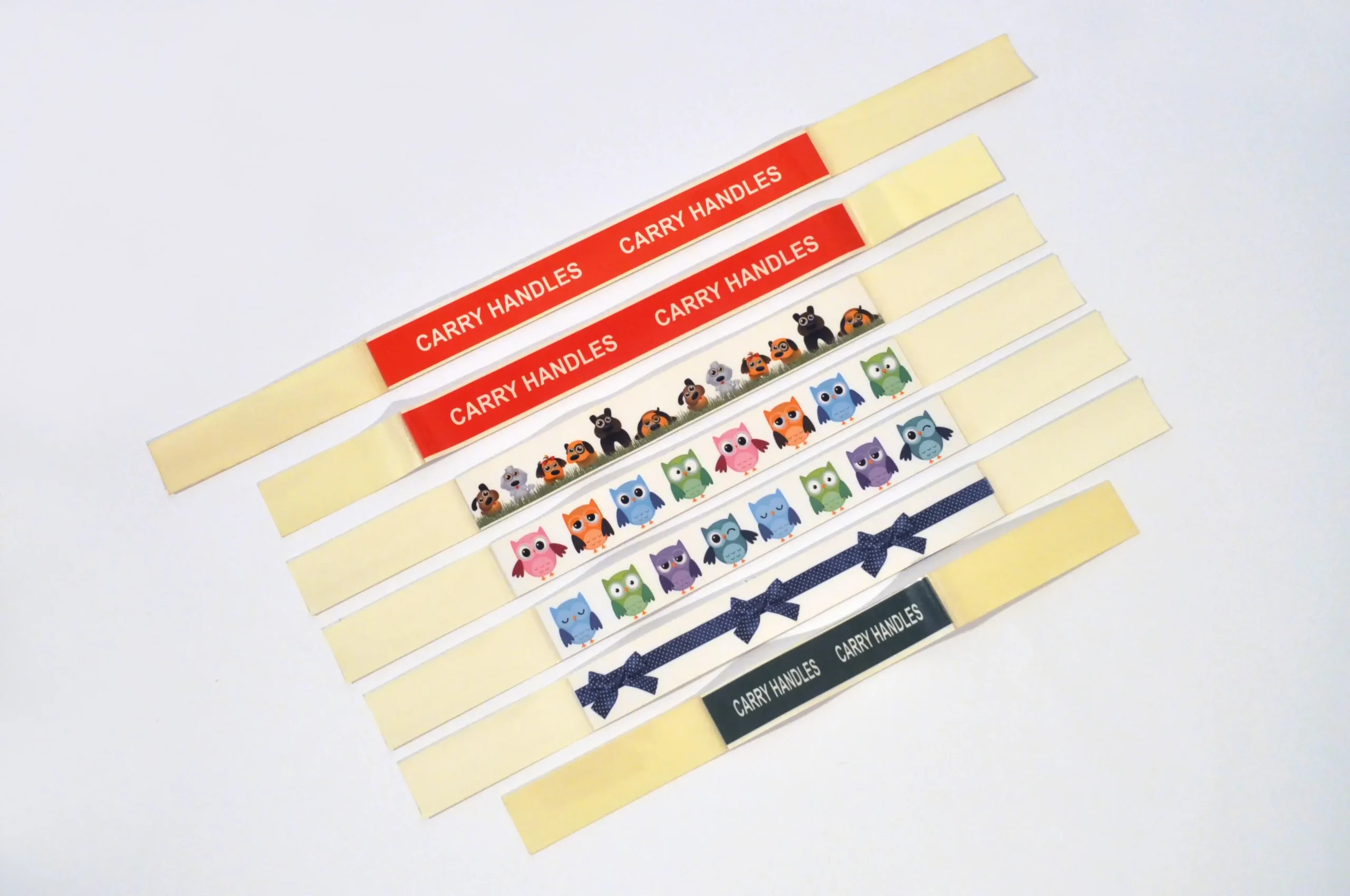 Adhesive carry handles in assorted designs and colors, with customizable printing, displayed in strips for packaging use.